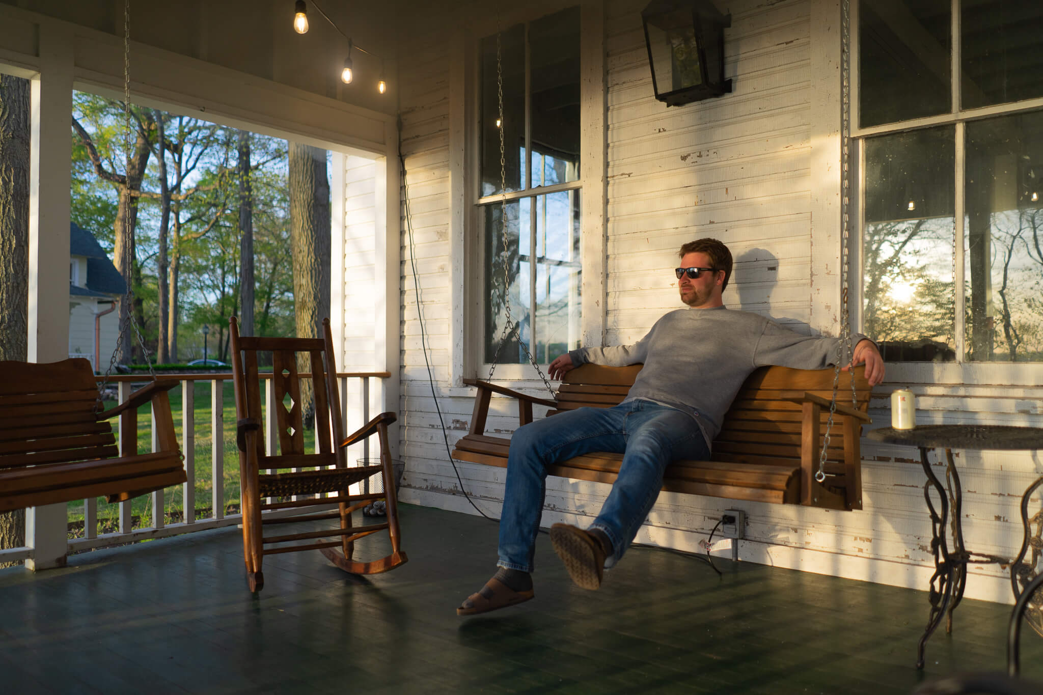 Dustin Mix lounges on the original front porch during a sunset over Lake Maxincuckee.
